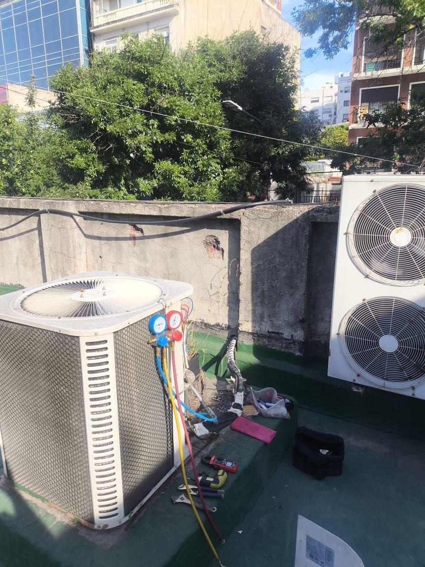 Dos condensadoras de gran porte en una terraza, una de ellas con los manómetros conectados durante el service